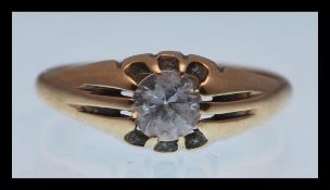 A hallmarked 9ct gold ring with a brilliant cut white stone with reeded shoulders. Hallmarked