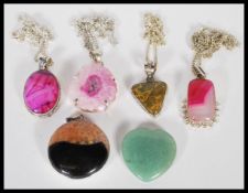 A group of contemporary silver plated semi precious stone necklace pendants along with a green stone