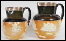 A graduating pair of Royal Doulton Lambeth harvest ware salt glazed jugs having silver hallmarked