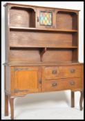 A 1920's Arts & Crafts revival oak dresser having coloured leaded glass cabinet to the centre of the