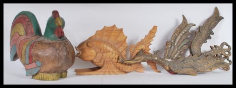 An over sized carved wooden painted chicken together with a carved Carp raised on a naturalistic