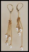 A pair of 9ct gold drop earrings consisting of graduating chains set with white pearls to the
