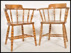 A pair of Victorian beech and elm wood smokers bow armchairs being raised on ring turned legs united