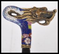 A Chinese tapering walking cane having an enameled cloisonne on copper knop modelled the head of a