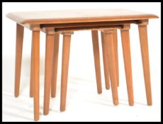 A retro 20th Century elm and beech wood nest of three graduating tables in the manner of Ercol, each