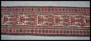 A 20th Century Persian Islamic knotted runner rug having a beige ground with red geometric