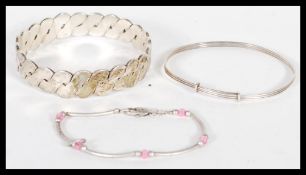 A silver bangle having crossover decoration allround with another two silver bracelets one having