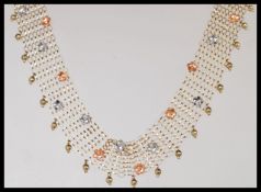 A stamped 375 9ct gold mesh choker style necklace with small silver tone and copper tone flower