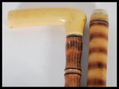 Two 20th Century walking sticks to include an unusual hollow bamboo walking stick which double as