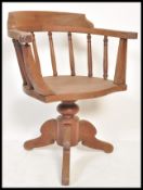 An early 20th Century Edwardian oak captains chair raised on quadruped base with turned rail