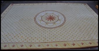 A large 20th century floor rug being originally retailed by Harrods having a beige ground with red