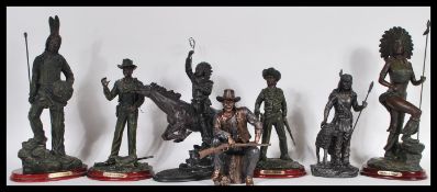 A collection of bronzed resin figurines of Native Americans and cowboys raised on plinth bases, most