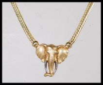 A 9ct gold necklace with a flat link chain attached to a pendant in the form of an elephant. Stamped