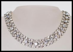 A silver white metal choker necklace set with three rows of white stones with a lobster clasp.