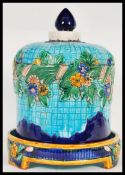 A majolica bell shaped cheese dish and cover. The cover on turquoise ground and decorated with