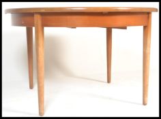 A retro 20th Century teak wood circular extendable dining table, fold out leaf raised on shaped