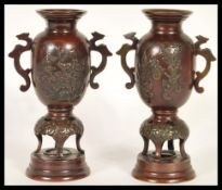A pair of 20th Century Chinese decorative bronzed urns having shaped twin handles with embossed