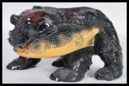 A 20th Century Canadian hand carved wooden fine large figurine in the form of a bear catching salmon