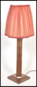 A 1930's Art Deco oak table lamp being raised on a square base with shaped column and shade atop.