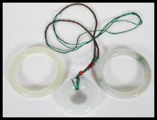 A group of Chinese green jade / green stone jewellery to include necklace pendant of roundel form on