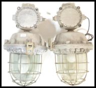 A pair of retro 20th Century large industrial factory bulk cage lights, having a cast iron body,