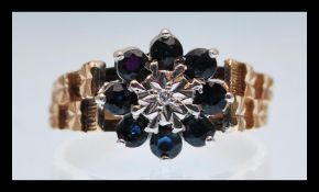 A hallmarked 9ct gold ring set with a flower head with a white central stone surrounded by blue