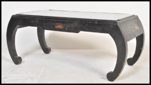 A Chinese black lacquer coffee table raised on scrolled legs with single drawer to front having