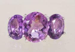 A sterling silver substansial three stone amethyst ring having three faceted purple stones in claw