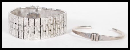 Two silver bangles one being a panel bracelet with a open box clasp, stamped 925. The other having a