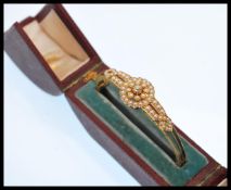 A 19th Century Victorian gold and pearl hinged bangle bracelet set with a central old cut diamond
