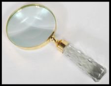 A large brass cased magnifying glass having a faceted glass tapering handle.