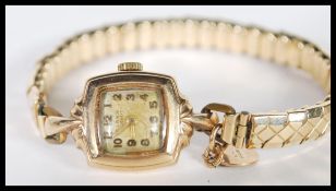 A 9ct gold ladies cocktail dress watch set to a rolled gold expanding bracelet. The watch with
