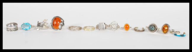 A selection of silver rings to include a ring set with an amber stone, a ring with plaited design, a