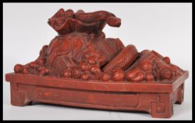 A 20th Century Chinese figurine featuring a snake emerging through a sack surrounded by scrolls