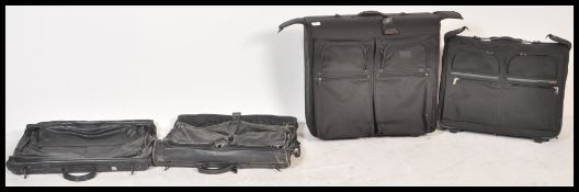 Four Tumi suitcases to include two black leather travel bags, and two larger black canvas bags one