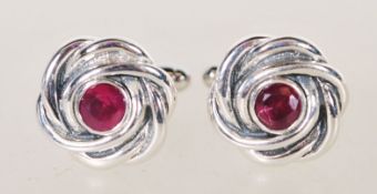A pair of sterling silver cufflinks of knot design having central rubies / faceted ruby stones.
