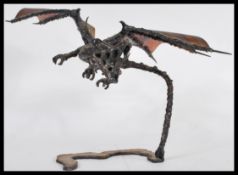 A cast metal sculpture of an armoured dragon in flight in the the gothic taste raised on a