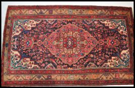 A Persian Islamic Zanjaan hand made wool floor rug / carpet having a red ground with geometric