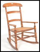 A 19th Century Victorian fruitwood and cane work rocking chair, cane seat panel between open arms