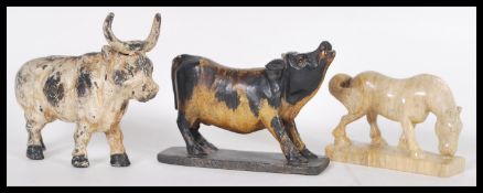 A vintage 20th Century cast iron money box in the form of a horned cow being painted with white