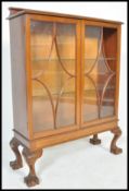 A 1930's mahogany Queen Anne revival china display cabinet being raised on claw and ball feet with