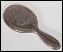 A silver hallmarked ladies vanity mirror having an Art Nouveau inspired back in relief. 27cm long.