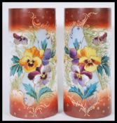 A pair of early 20th Century milk glass vases of cylindrical form having hand painted decoration