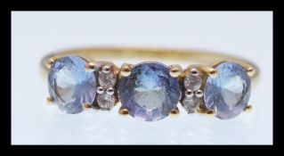 A hallmarked 9ct gold ring prong set with three brilliant cut light blue stones having four white