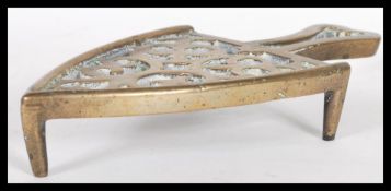 A 19th Century Georgian brass trivet stand having raised on three feet with shaped split handle