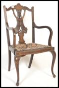 An early 20th Century inlaid mahogany elbow chair, with pierced fan slat back, shaped arms with
