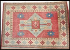 A vintage 20th Century tribal woven carpet rug having a red ground with a blue geometric