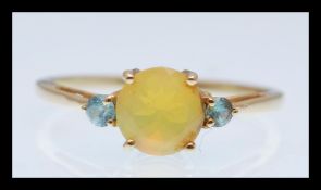A hallmarked 9ct gold ring prong set with a brilliant cut yellow opalescent stone flanked with two