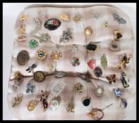 A collection of vintage and retro 20th Century brooches applied to a cushion, to include dress