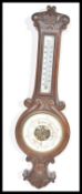An early 20th Century oak barometer and carved scroll work. The enamel dial having painted details